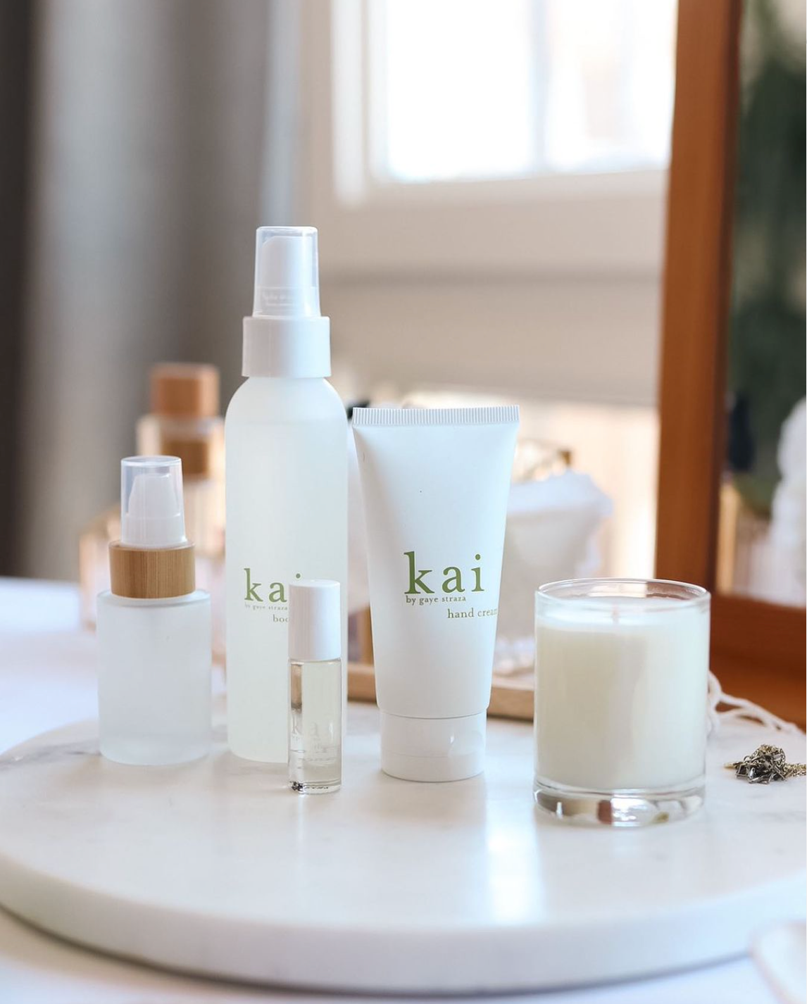 Kai skincare and fragrance products with hand cream, body spray, perfume oil, and candle on vanity table